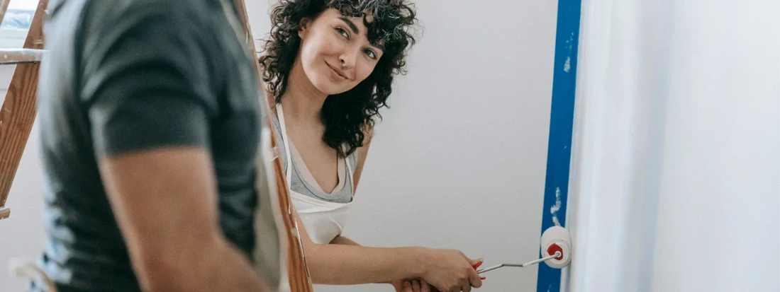 Woman smiling at the camera while painting a room, representing everyday movement and joint comfort supported by Supple joint supplements.