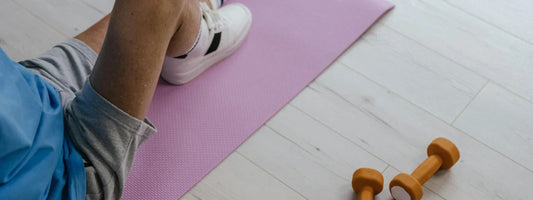 A man sitting on a yoga mat with one leg raised with his foot placed on the mat, representing active lifestyles supported by Supple joint health supplements with glucosamine, chondroitin, and boswellia.