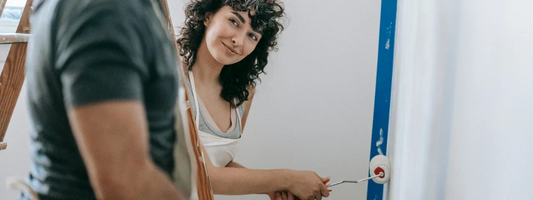 Woman smiling at the camera while painting a room, representing everyday movement and joint comfort supported by Supple joint supplements.
