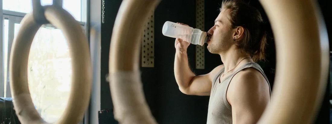 Man drinking from a water bottle at the gym after a workout, representing hydration and joint support with Supple joint health supplements.