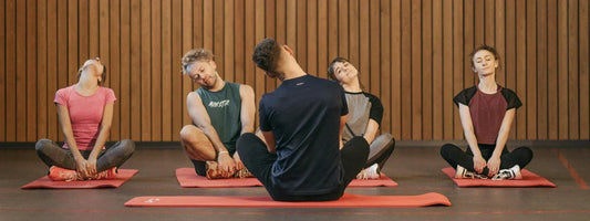 A group fitness class of people sitting on mats stretching, representing active lifestyles supported by Supple joint health supplements with glucosamine, chondroitin, and boswellia.