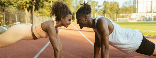 A man and woman facing each other stretching and doing planks on a track field, representing active lifestyles supported by Supple joint health supplements with glucosamine, chondroitin, and boswellia.